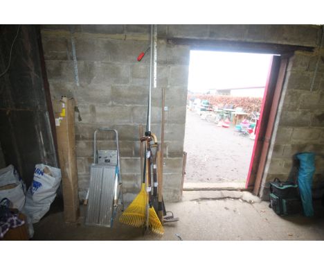 A bundle of long handled tools including pick axe and rakes etc 