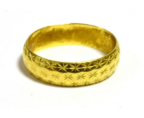 22CT GOLD WEDDING BAND   5.1mm wide, continuously decorated with bright cut star engraving, ring size K.  Hallmarked 916 Lond