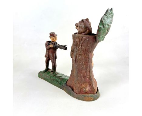 This item is a vintage cast iron mechanical money bank, designed with a Native American hunter and bear theme. The bank depic