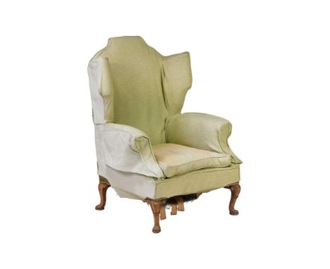 A WALNUT AND UPHOLSTERED WING ARMCHAIRIN GEORGE II STYLE, FIRST HALF 20TH CENTURYThe green loose cover over wool and woven ta