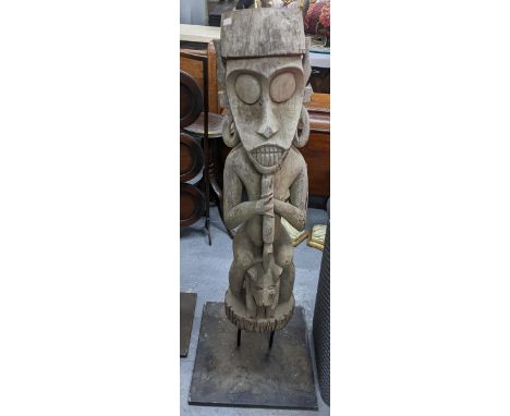 A hardwood carved tribal figure depicting a seated figure clutching a staff, on a metal display base, 111.5cm hLocation:If th