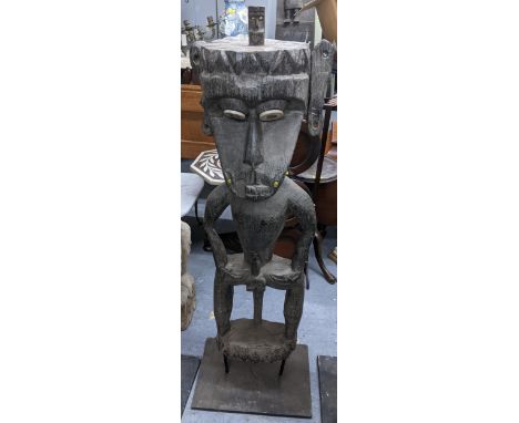 A hardwood carved tribal figure, having a small figure atop the head, in a standing posture with hands on hips, 120cm hLocati