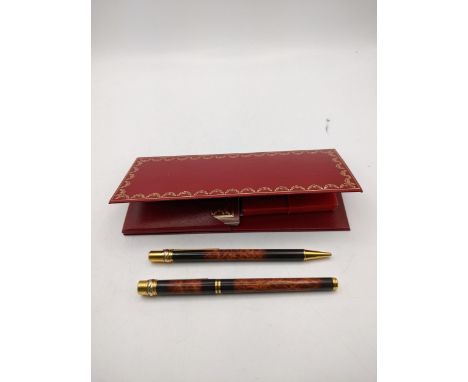 A Cartier rollerball and ballpoint fountain pen set in a brown and black lacquer case with a case, paperwork together with a 