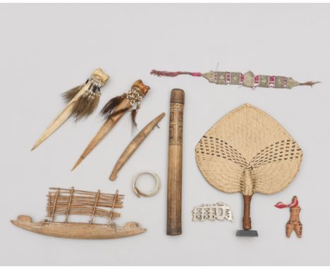 A collection of various ornamets and objects, among which an Asmat bamboo pipe, a model Massim canoe, a Fiji fan and two bone