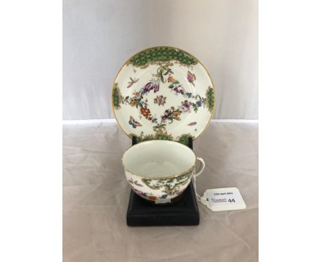 A Hoschst teacup and saucer, circa 1770, painted to the rim with green diaper panels suspending floral swags, scattered insec