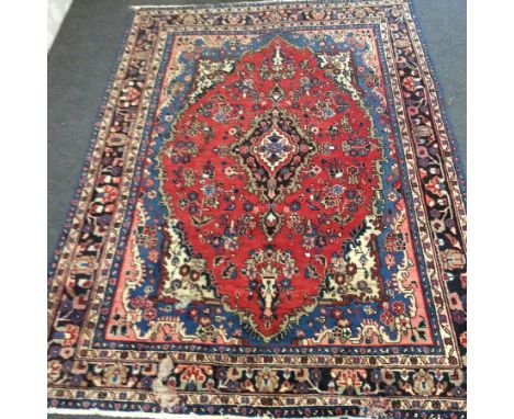 A Qashqai carpet with central red ground floral medallion within a multi figured border, 306cm x 216cm CONDITION REPORT: A li