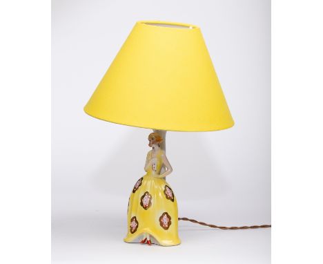 Style of Katzhutte, mid 20th Century/A ceramic lamp, the base in the form of a girl in a yellow floral dress, with yellow sha