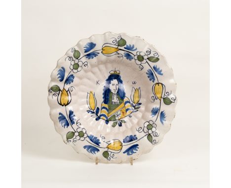 A Dutch Delft Royal portrait dish, of lobed form, painted in blue, green and yellow with a central portrait of King William w