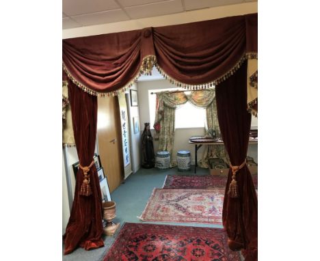 A pair of red velvet swagged curtains with tie backs, 244cm x 244cm and the pole