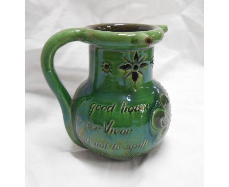 A C.H Brannam Barnstaple Art Pottery puzzle jug with incised fish decoration and motto on a green glaze ground
