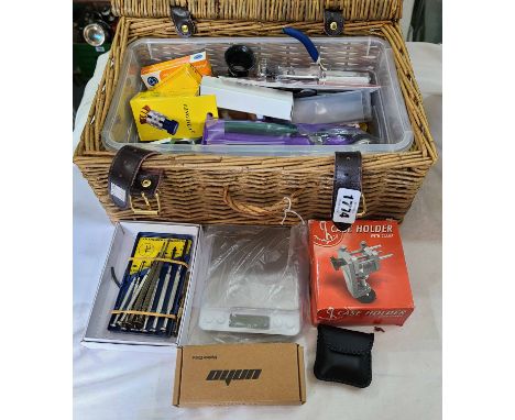 A wicker basket containing a quantity of watch tools and clamps including watch case openers and case holder, metal band link