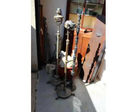 AN OLD BRASS FLOOR STANDING OIL LAMP, Corinthian column support and square step base terminating in paw feet, 151cm high toge