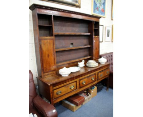 A GEORGE III OAK DRESSER the boarded shelf back with a pair of cupboards above three drawers with shaped apron frieze upon sq