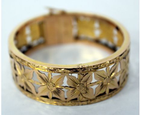 AN 18 CARAT GOLD HINGED BANGLE, flowerhead design, clasp stamped 18K