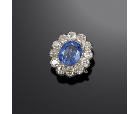 A sapphire and diamond cluster ring, the oval-shaped sapphire weighs approximately 4.10cts, set within a silver cut-down coll