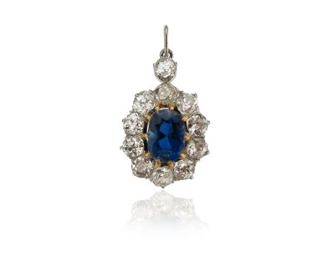 A sapphire and diamond cluster pendant, the oval-shaped sapphire set in a surround of old circular-cut diamonds, surmounted b