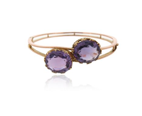 A late Victorian yellow gold bangle, set with two oval-shaped amethysts, 5.5cm inner diameter