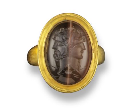 A sard intaglio depicting the conjoined heads of Jupiter and Juno, in the Roman style, set in a gold ring, intaglio 2 cm high