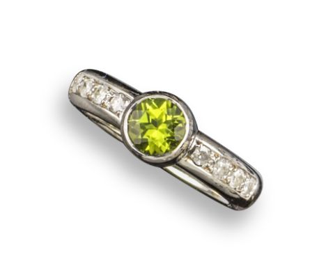 A peridot and diamond half hoop ring, set with a circular-cut peridot within diamond shoulders in 9ct white gold, London hall