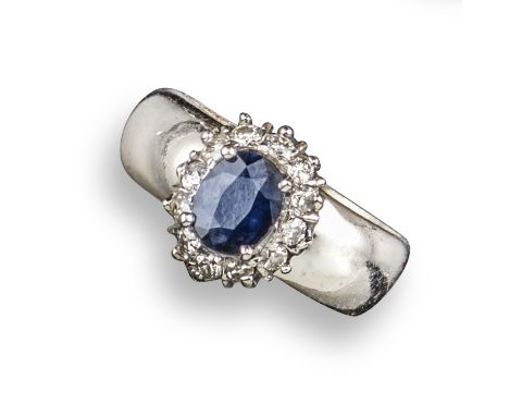 A sapphire and diamond cluster ring, the oval-shaped sapphire is set within a surround of round brilliant-cut diamonds in 18c