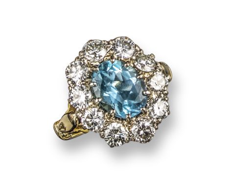 An aquamarine and diamond cluster ring, the oval-shaped aquamarine is set within a surround of round brilliant-cut diamonds i