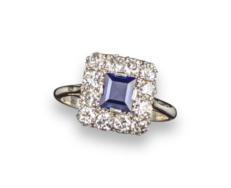 A sapphire and diamond cluster ring, the square sapphire set within a surround of round brilliant-cut diamonds in platinum, s