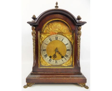 A Mahogany-Carved Bracket Clock, the clock having a silvered chapter ring with applied cherubs and floral motif to surround, 