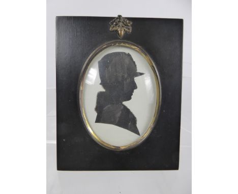 An Antique Silhouette Portrait, wearing a hat and fur collar in black wooden frame, verso there is a newspaper cutting of Fir