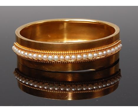 A yellow metal and seed pearl set hinged bangle, with safety chain, unmarked but tests as approx 18ct, gross weight 31.8g, di
