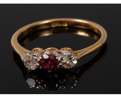 An 18ct gold, ruby and diamond three stone ring, arranged as a centre round cut ruby flanked to either side with a claw set s