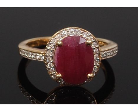 A modern 9ct gold, ruby and diamond point set dress ring, the four claw set oval cut ruby in a surround of diamond points, th