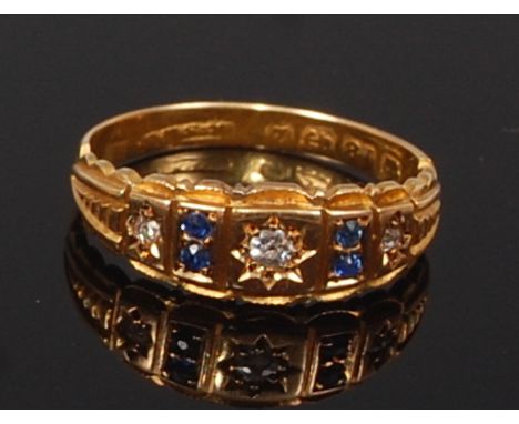 A George V 18ct gold, sapphire and diamond ring, the three graduated old cut diamonds each dispersed with twin small sapphire