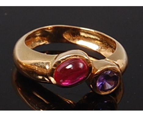 A modern 18ct gold, ruby and tanzanite set ring, arranged as a cabochon ruby and round cut illusion set tanzanite, the tanzan
