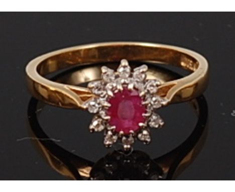 An 18ct gold, ruby and diamond flower head cluster ring, the oval cut ruby within a surround of twelve diamond points, 3.6g, 