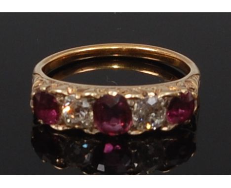 An Edwardian 15ct gold, ruby and diamond five stone ring, arranged as three round cut rubies, each dispersed with a single ol