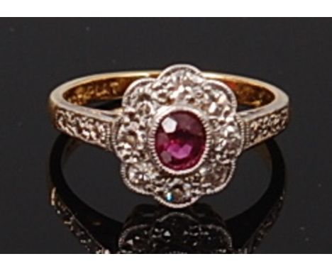 An 18ct gold and platinum, ruby and diamond cluster ring, the oval cut ruby in a surround of eight pavé set old cut diamonds,