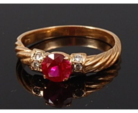 A modern 20ct gold, ruby and diamond ring, arranged as a four claw set round cut ruby weighing approx 0.8ct, flanked to eithe