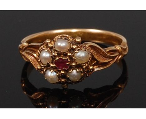 An early 20th century 18ct gold, ruby and seed pearl set dress ring, arranged as a cluster setting to leaf chased shoulders, 