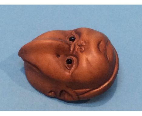 A carved netsuke in the form of a reversable child's face
