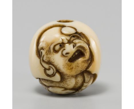 DOSHO: A FINE IVORY OJIME DEPICTING DARUMA WITH A TANKOBUBy Dosho (1828-1884), signed Doshosai 道笑斎Japan, Osaka, c. 1860Finely