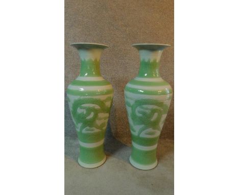 A pair of modern Kangxi style pale green and white glazed ceramic dragon vases. Signature to base. H.97cm 