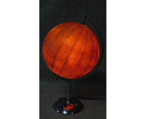 A vintage illuminated world globe lamp. Glass shade covered with paper globe sections. On a polished chrome stand with engrav