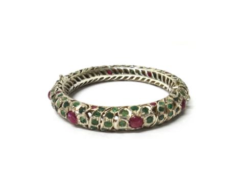 An Eastern cabochon ruby and emerald set circular hinged bangle, with a box.