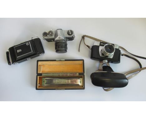 A Pentax Spotmatic camera, together with a Halina Paulette camera, a Zeiss Ikon camera and a German mouth organ, with the nam