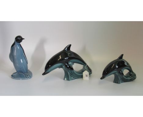 Three items of Poole pottery, to include: pair of graduated leaping dolphins, together with a penguin.