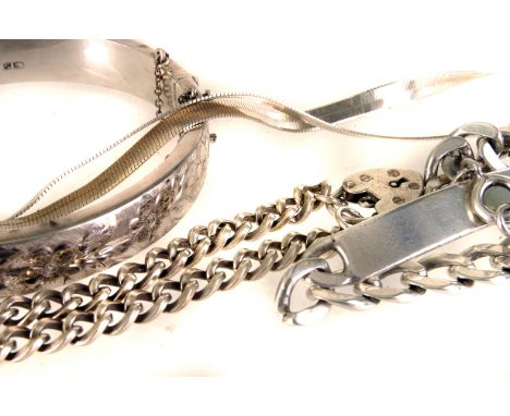 A collection of silver and white metal jewellery, including a bangle, two identity bracelets, a flattened link necklace, two 