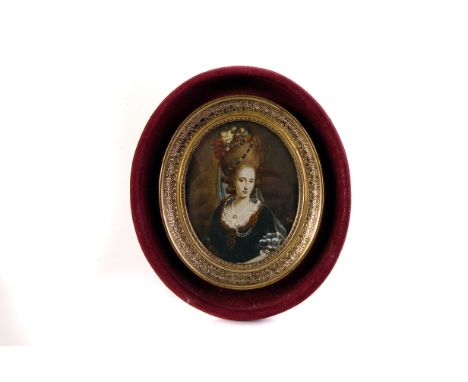 An oval portrait miniature,  depicting an elegant lady with pearl necklace and a floral headdress, with small undecipherable 