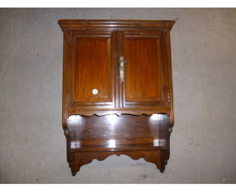 An Edwardian walnut wall cabinet, with two doors over bracket shelf