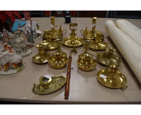 A collection of thirteen brass candle stick holder and a snuffer, some having unusual detailing and one fashioned as a rowing