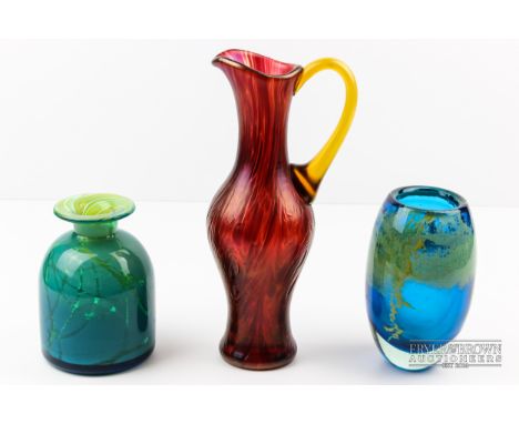 Two Mdina glass vases, one ovoid, the other of money bag form, blue, green and yellow colouration; and a ruby red glass ewer,